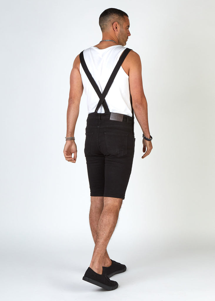 Rear pose to highlight slim overall straps that cross over at the back of Trafford biker dungaree shorts