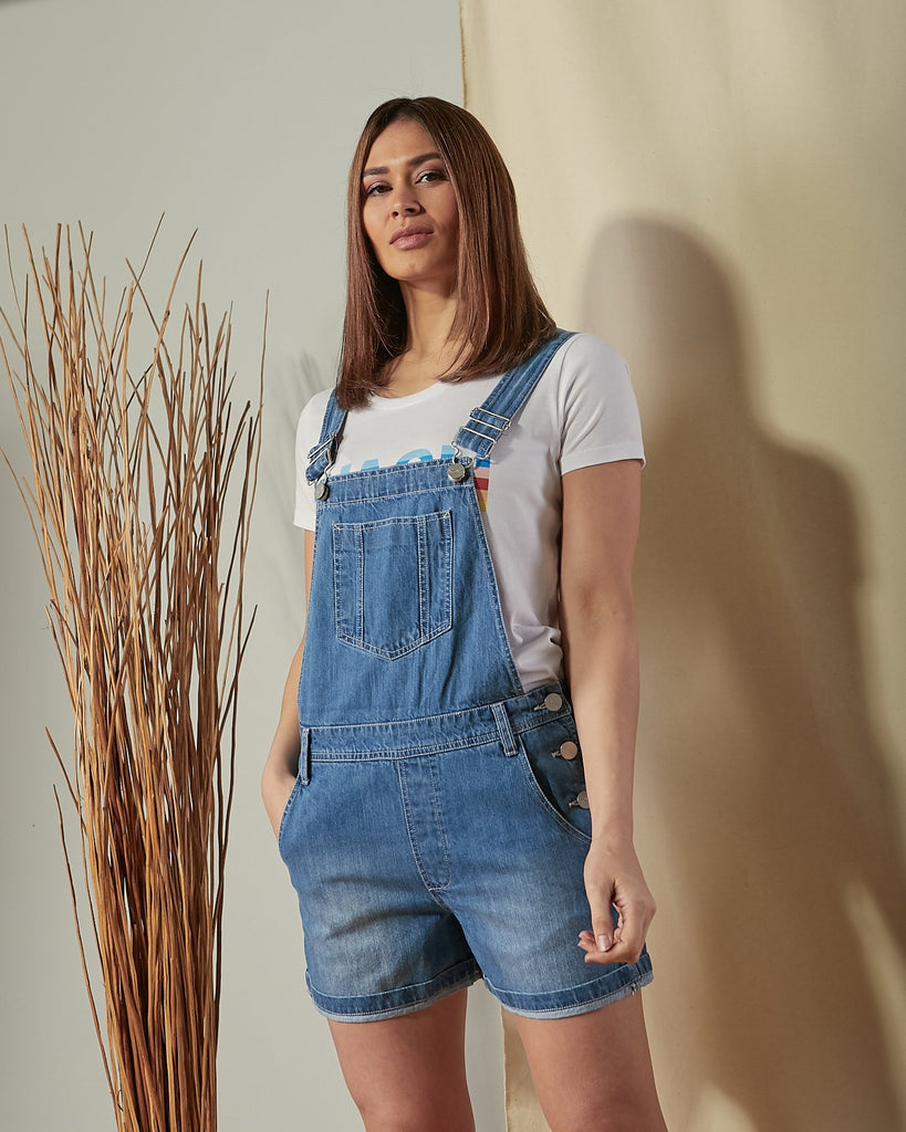 Two-thirds length slightly angled front view of Ava blue denim dungaree shorts.