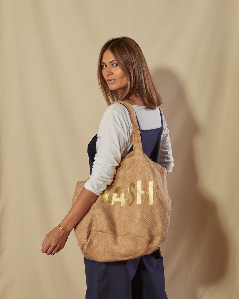 Close side view of Catherine navy blue overalls with tote bag over left shoulder.