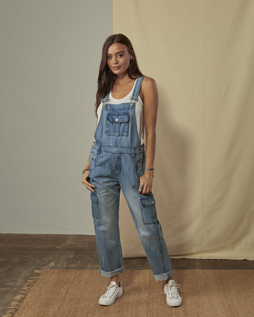 Front shot of Daphne stonewash denim dungaree with legs slightly rolled up with view of front, cargo & bib pockets.