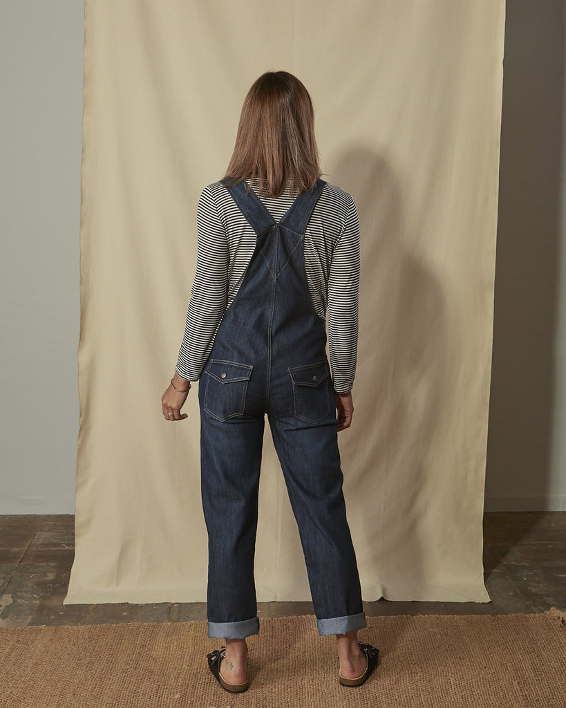 Full-length back shot of Dottie dark wash ladies regular fit dungarees with legs slightly rolled up.