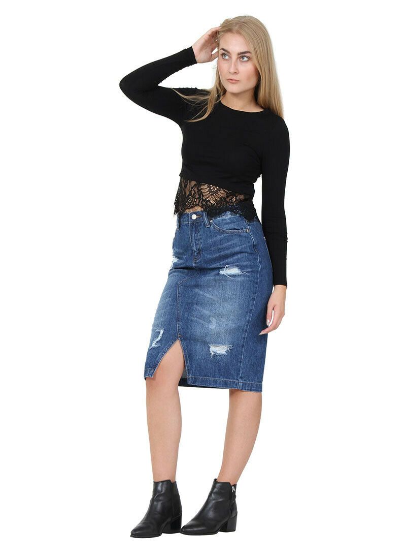 Angled frontal wearing classic mid-length slight stretch distressed denim skirt with clear view of front V-split, zip fly and belt loops.