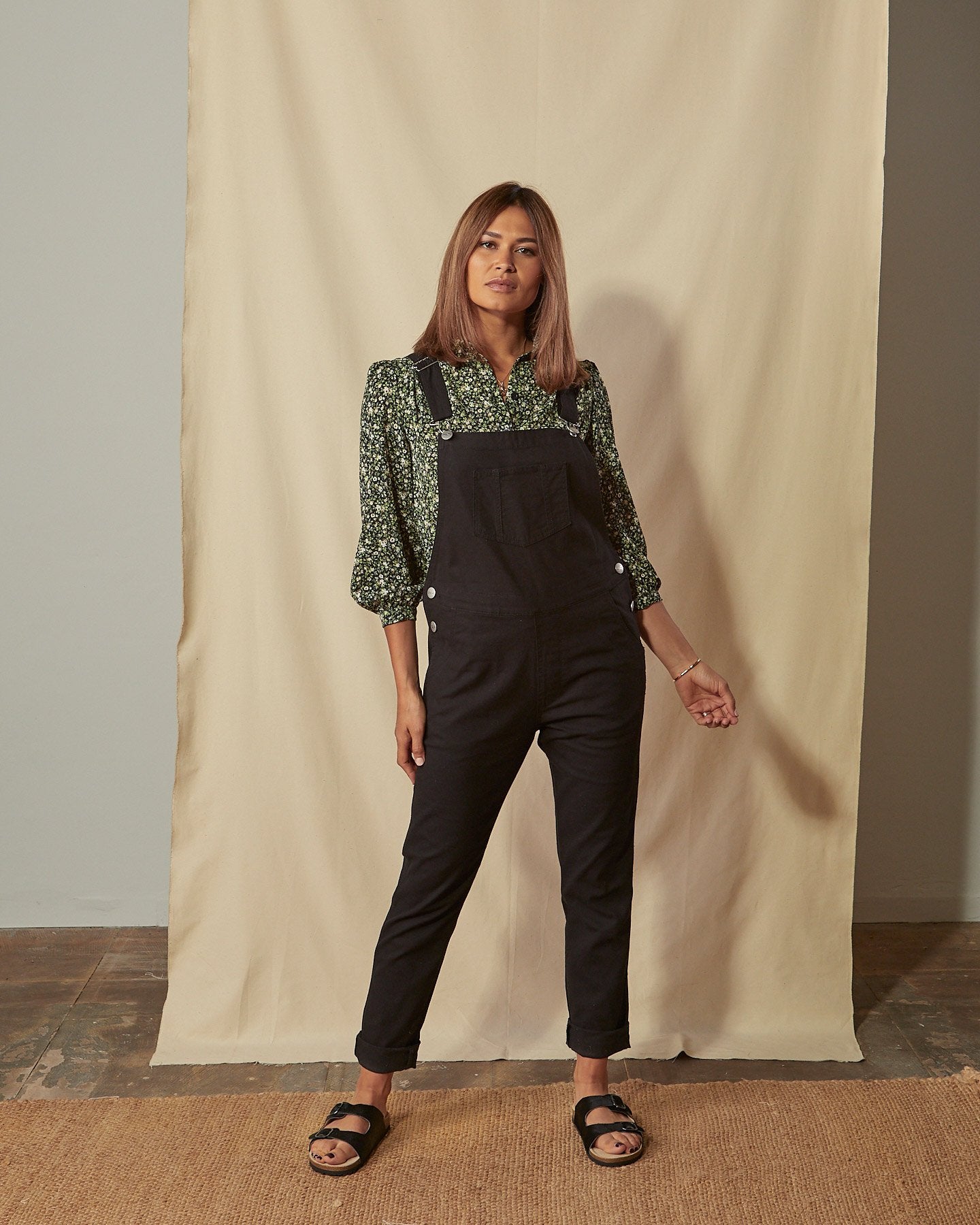 Full-length front view of model wearing Harper black organic cotton dungarees showing tapered leg.