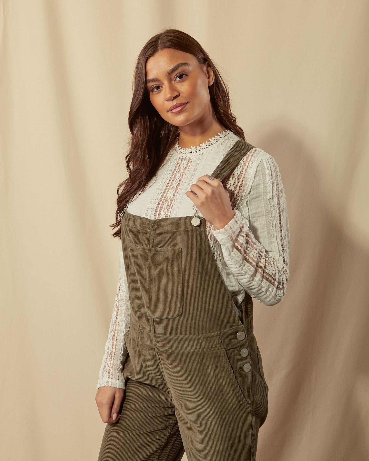 Full-length, slightly angled back view of model wearing Prue olive-green corduroy dungarees with view of back pockets and straps.