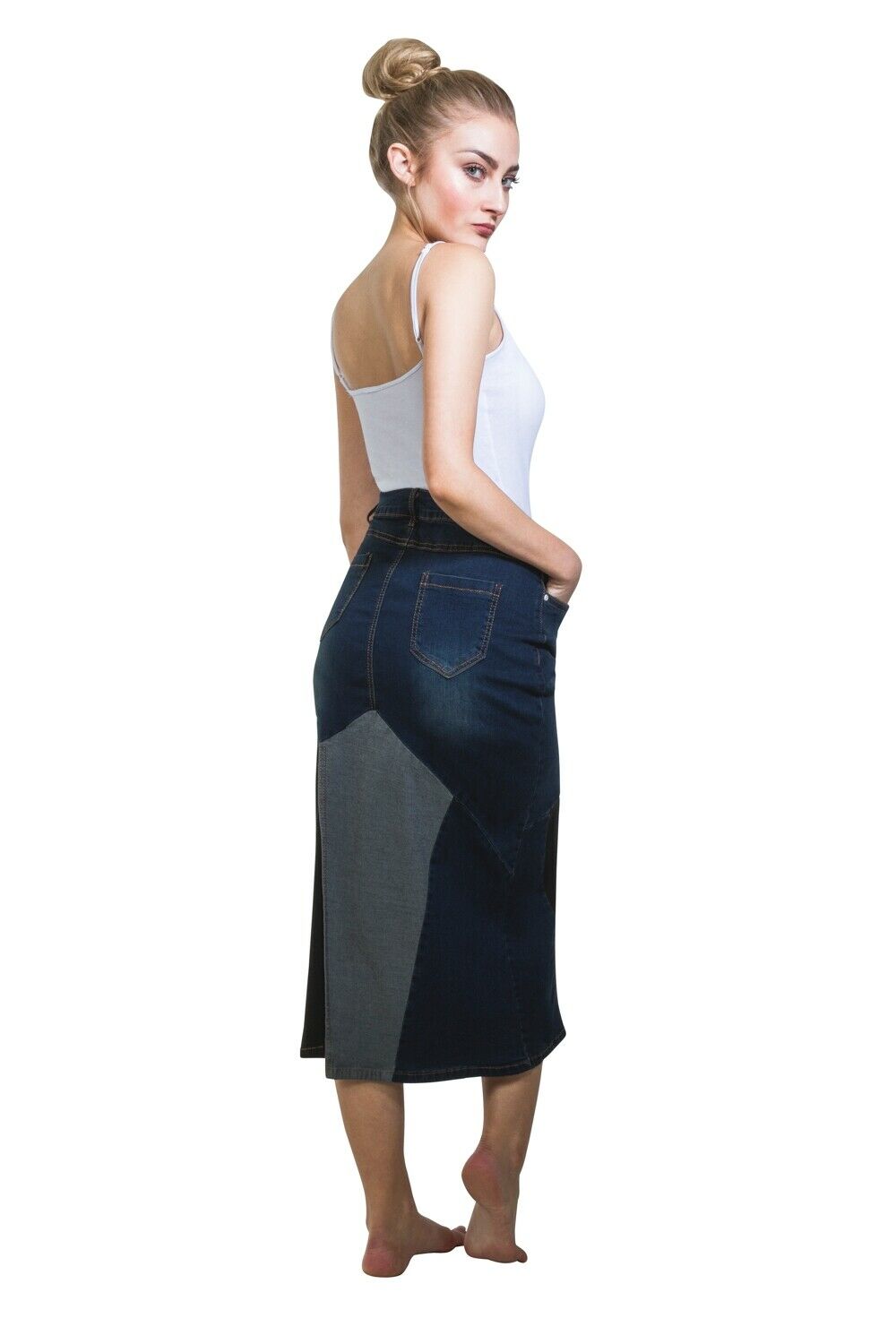 Angled rear view of indigo, black and pale blue denim midi-skirt with hands in front pockets and view of back pockets and belt loops.
