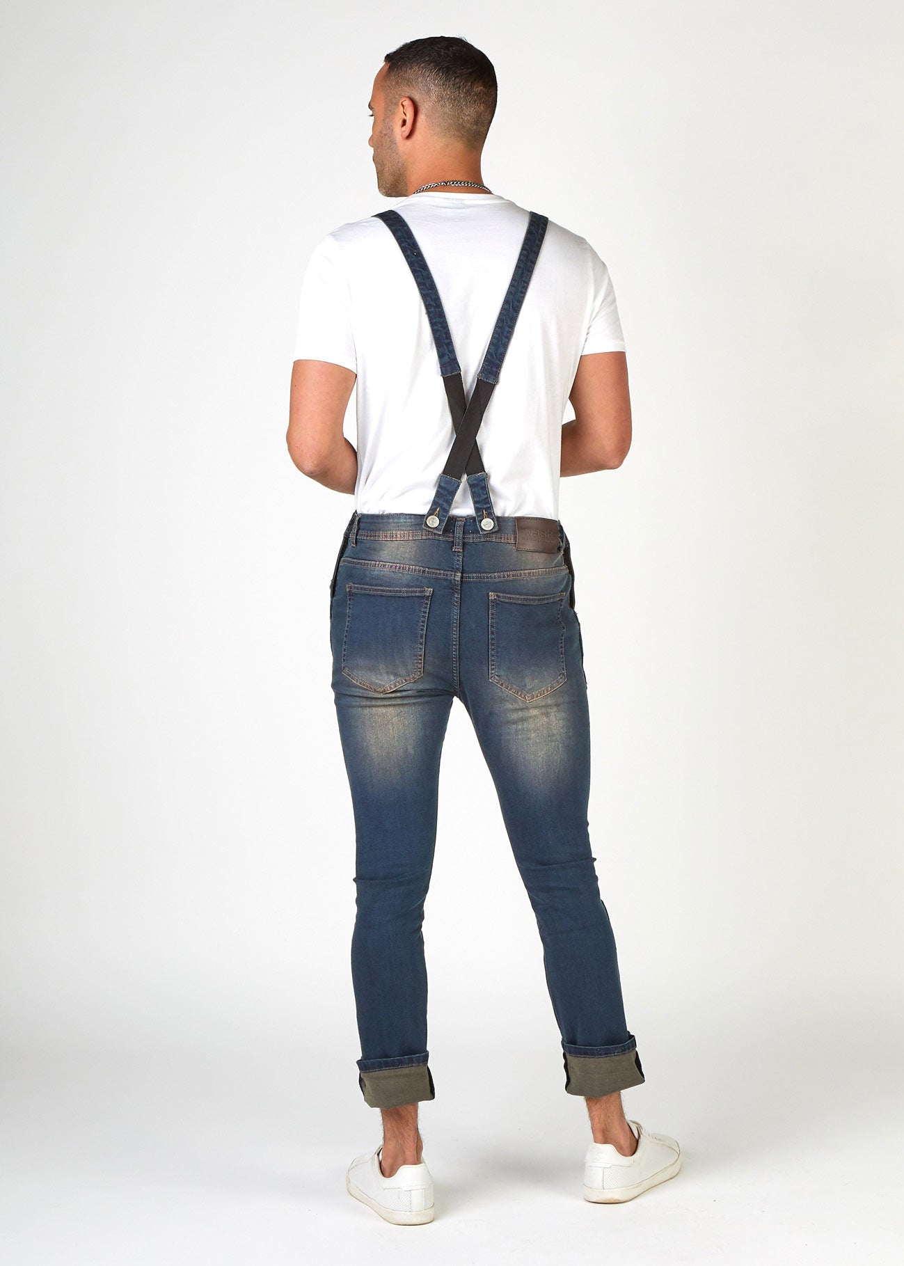 Full, slightly angled rear pose wearing versatile, Brooklands style bib overalls with turn-ups. Clearly showing adjustable & detachable straps.