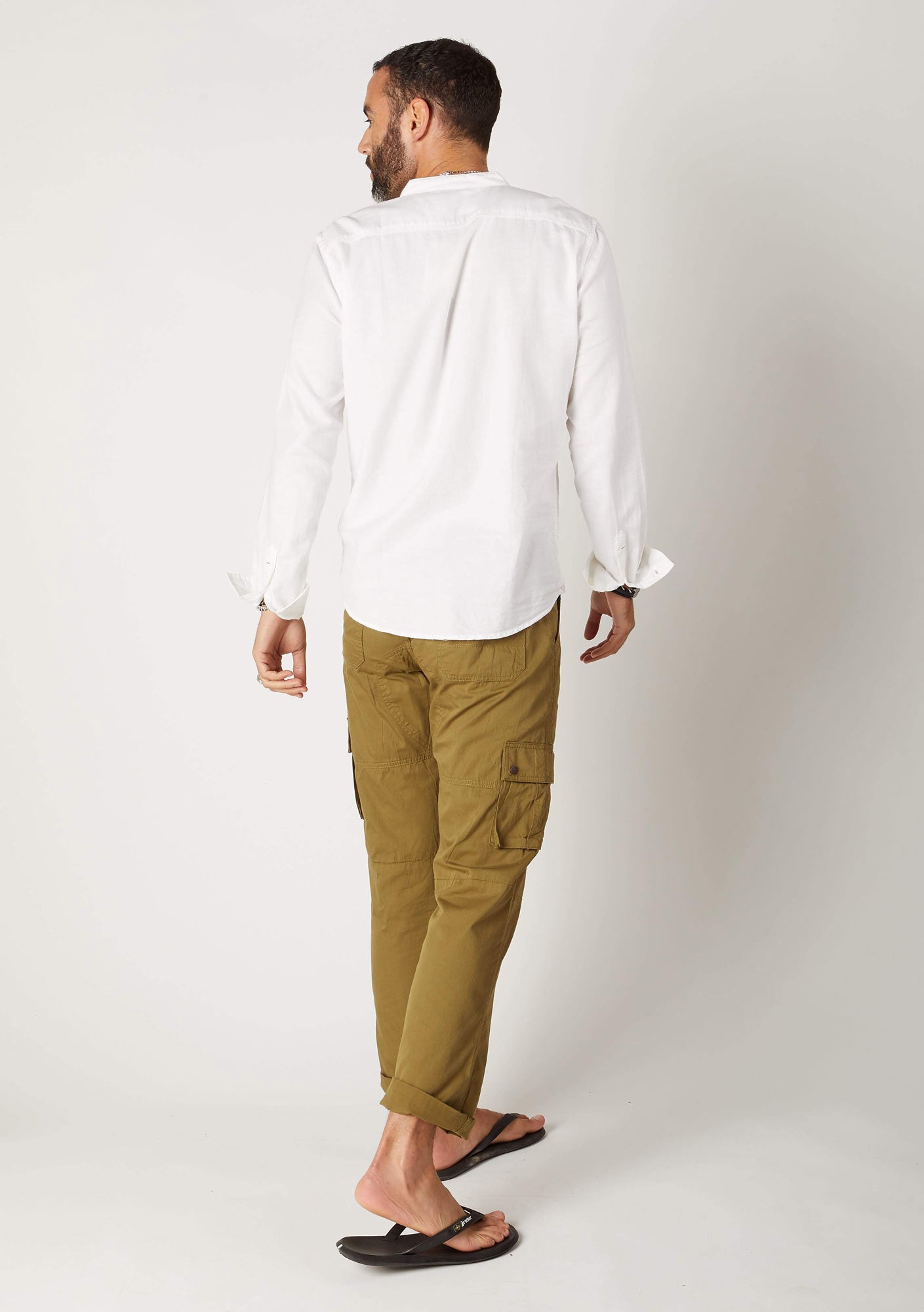 Back view of olive green, organic cotton combat trousers paired with white cotton sweater.