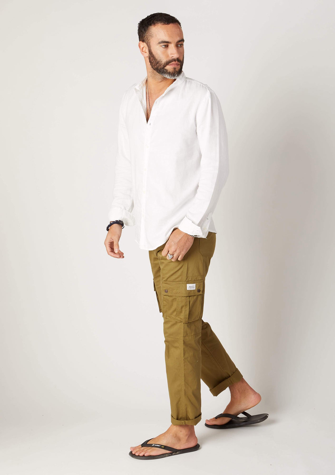 Walking pose, side-view of relaxed fit, organic cotton cargo trousers, with clear view of front cargo pockets.