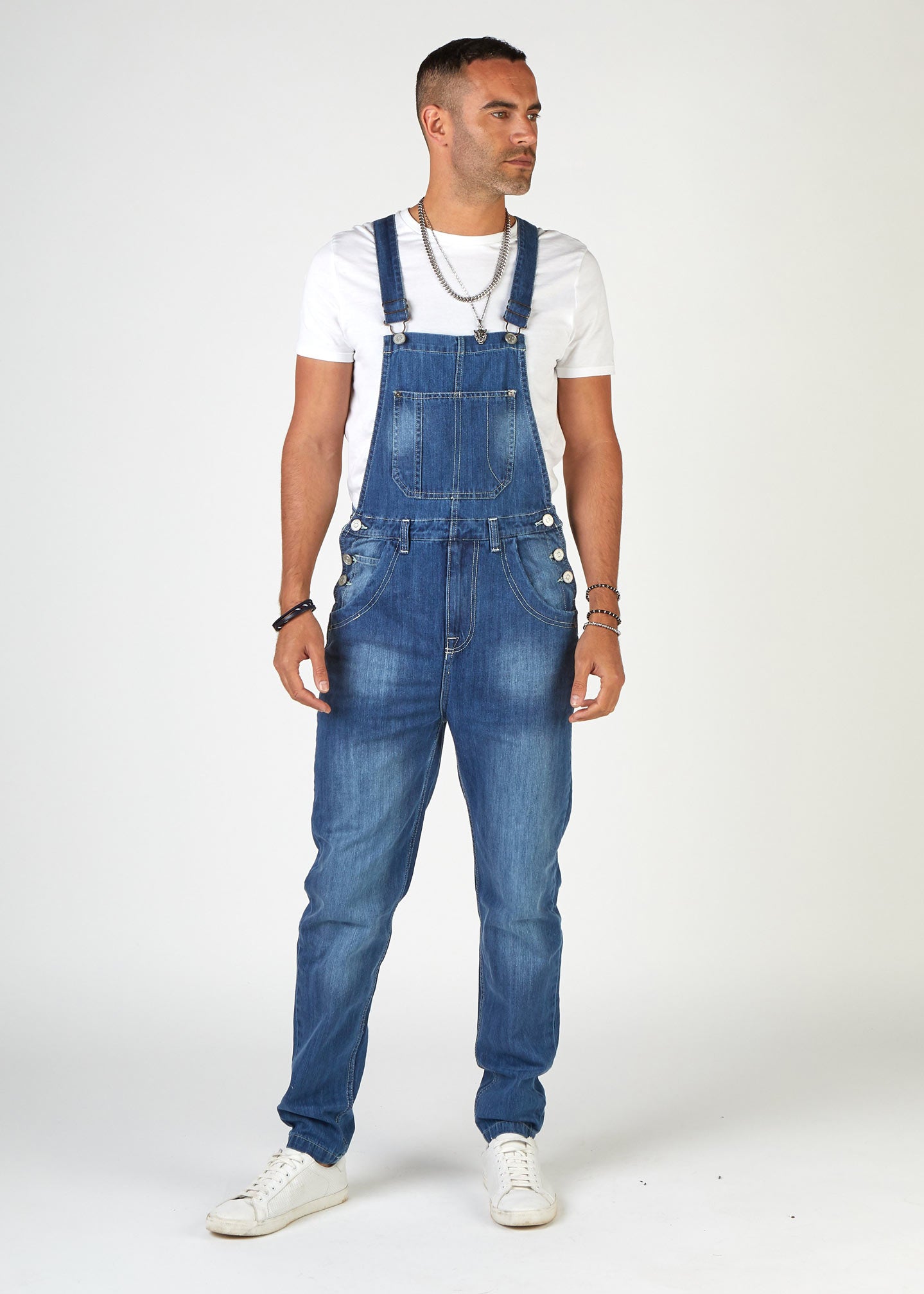 front, full-length pose, looking to model's left, wearing loose, midwash denim dungarees.