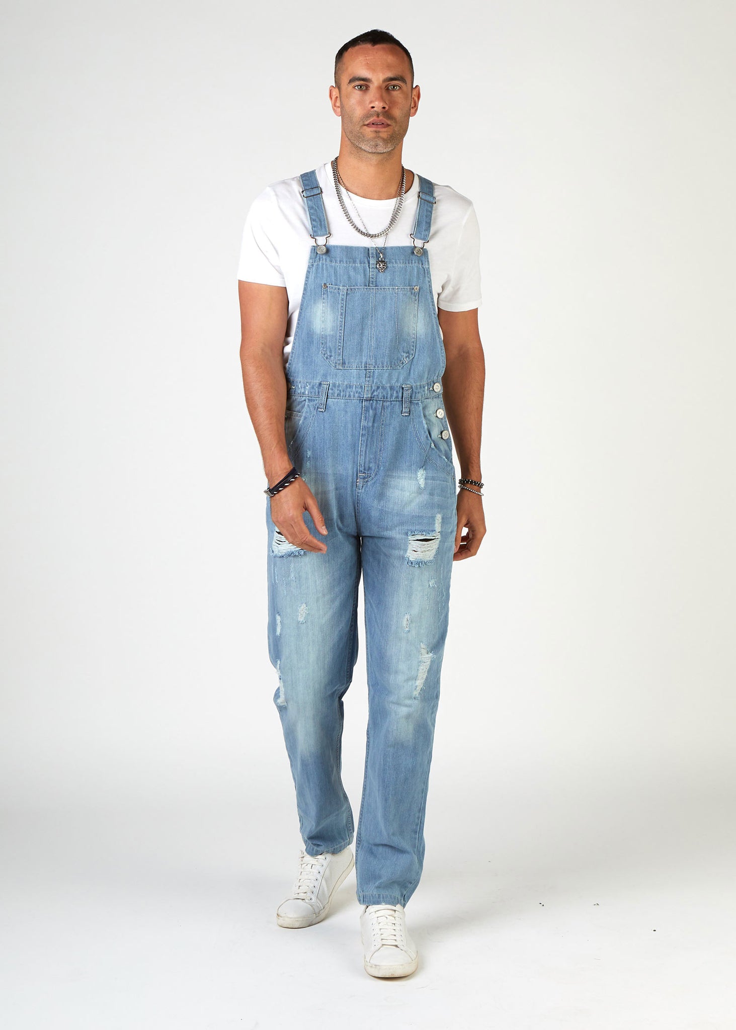 front, full-length walking pose, wearing loose, palewash, ripped denim dungarees.