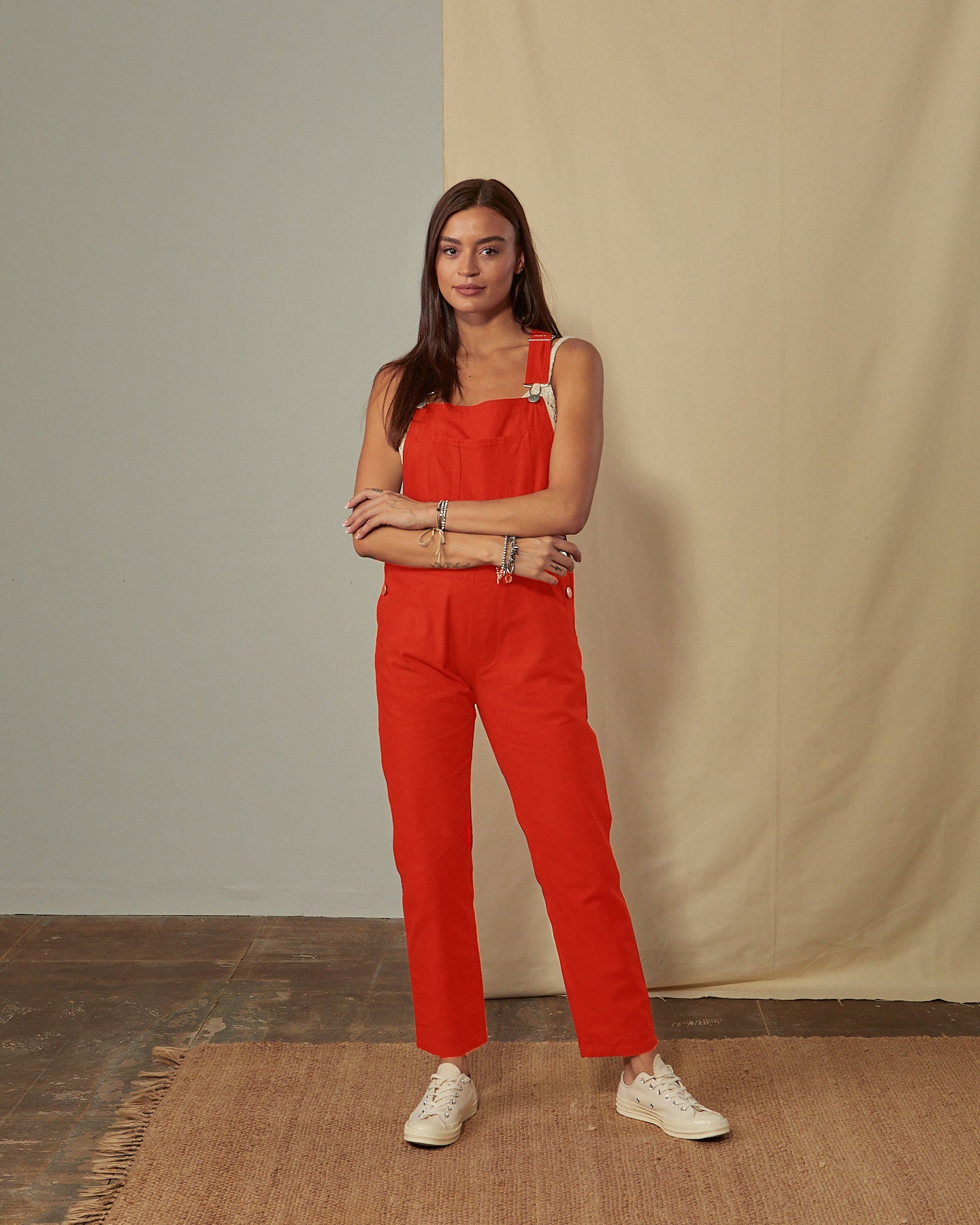 Full-length front view of model wearing Harper dark orange organic cotton dungarees with view of button fastening.