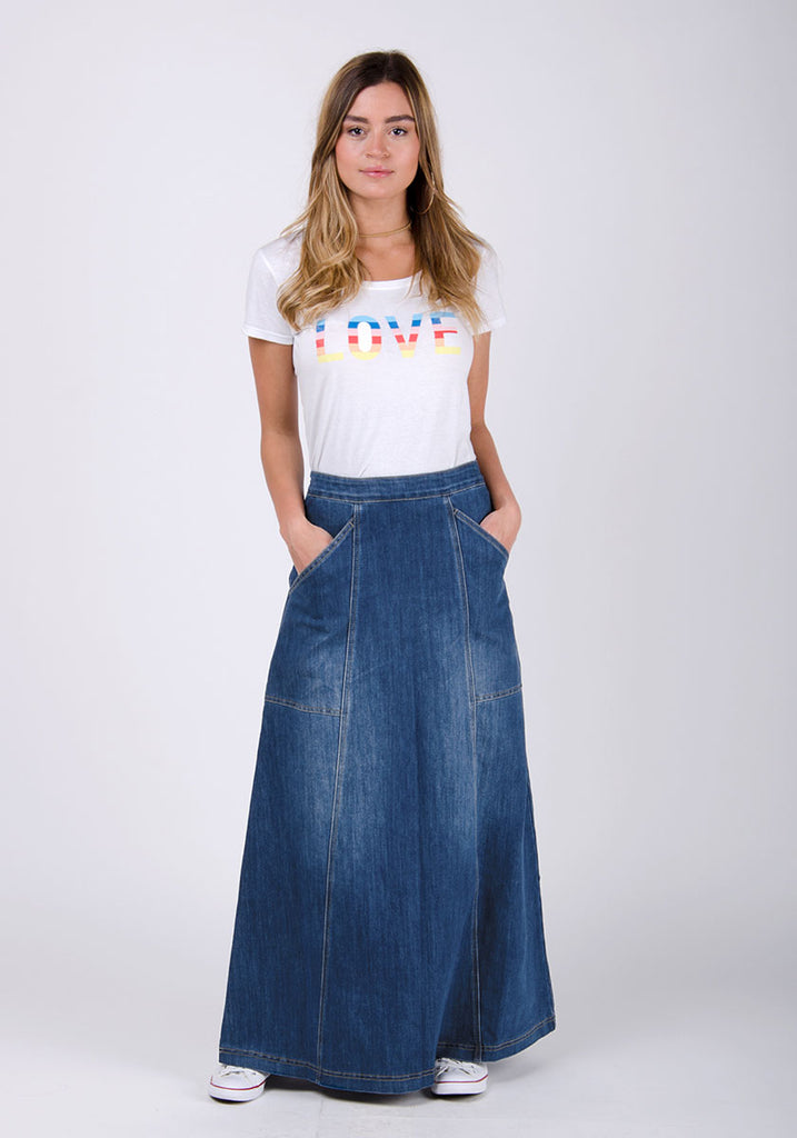 Full-length front view wearing stonewash mid-blue panelled denim long skirt paired with white t-shirt.