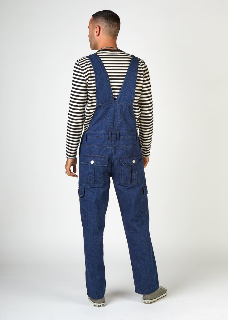 Back view of loose-fitting indigo bib-overalls with clear view of back pockets and back strap.