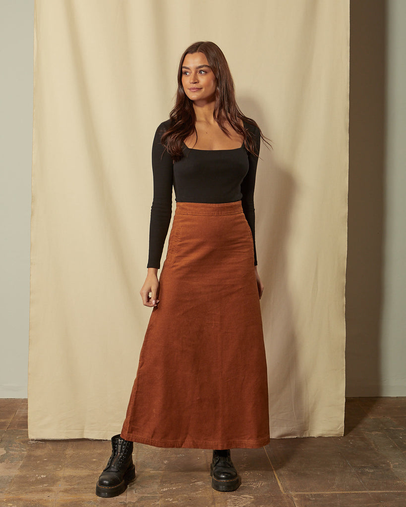 Full-length front view of model wearing Lottie brown corduroy maxi-skirt demonstrating A-line silhouette.