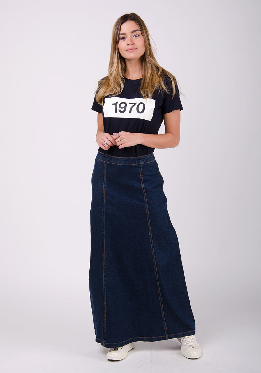 Front full-length shot model shot of panelled dark blue denim long skirt showing flared aspect.