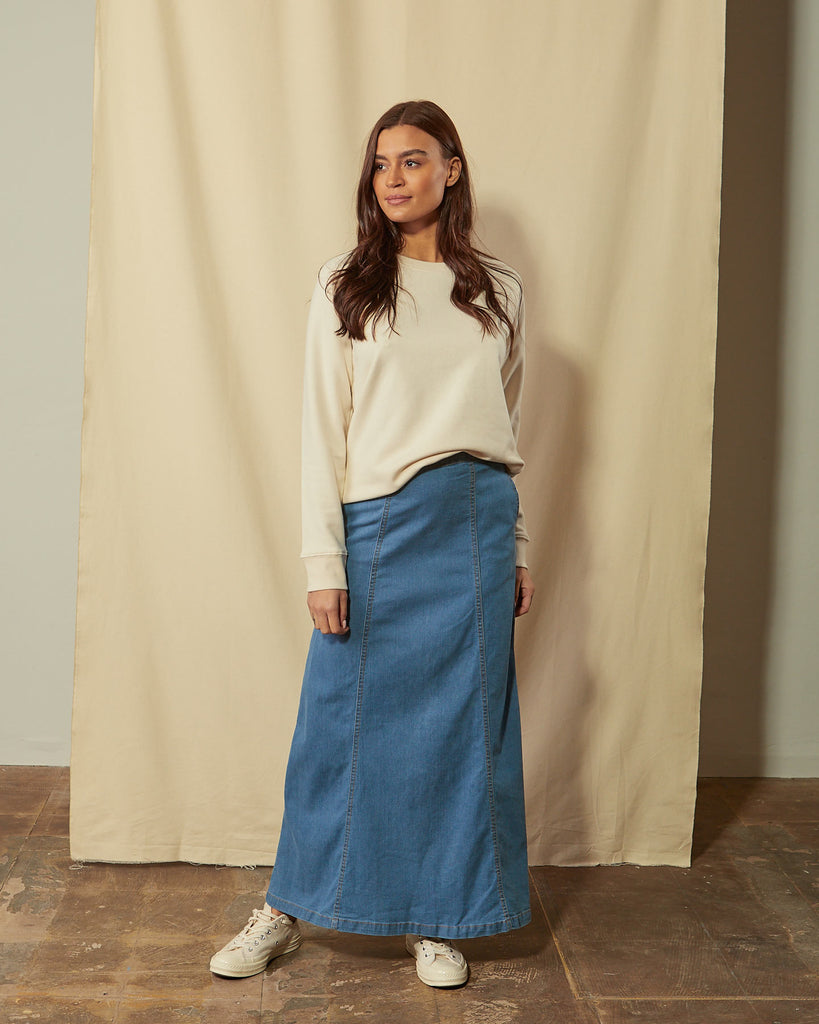 Back close-up view of panelled pale blue denim maxi skirt showing back zip and button fastening.