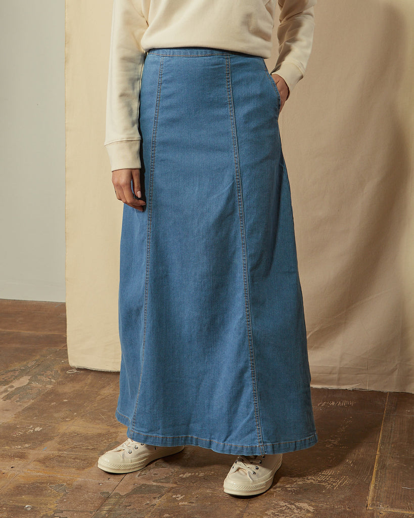 Front close-up view of panelled pale blue denim maxi skirt showing side pocket.