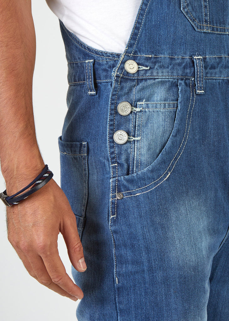 Focus on mid region of Bertie mid-wash denim dungarees showing 3-button side closure and side pockets.