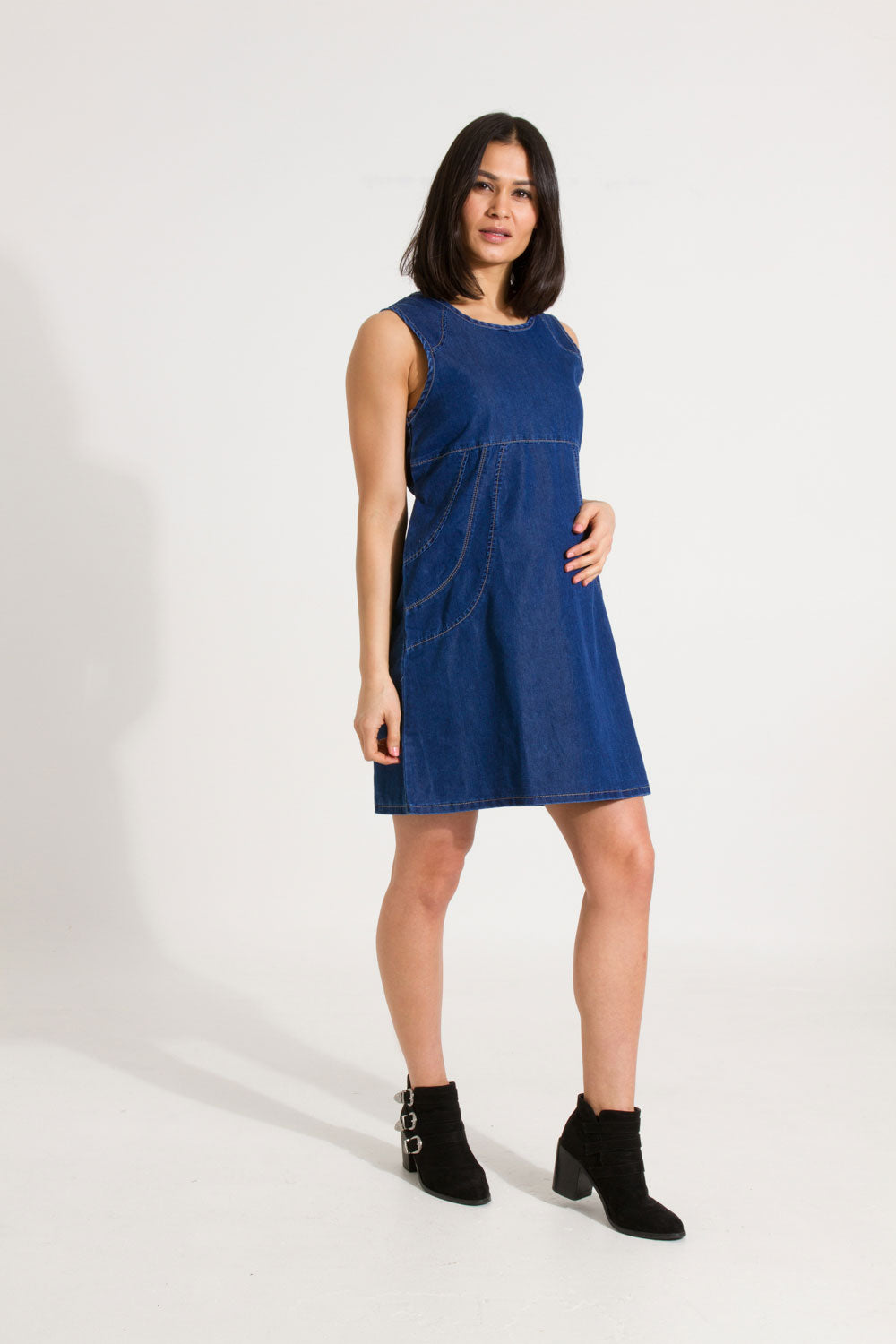Full-length slightly angled front view of Thelma soft denim blue pinafore maternity dress.