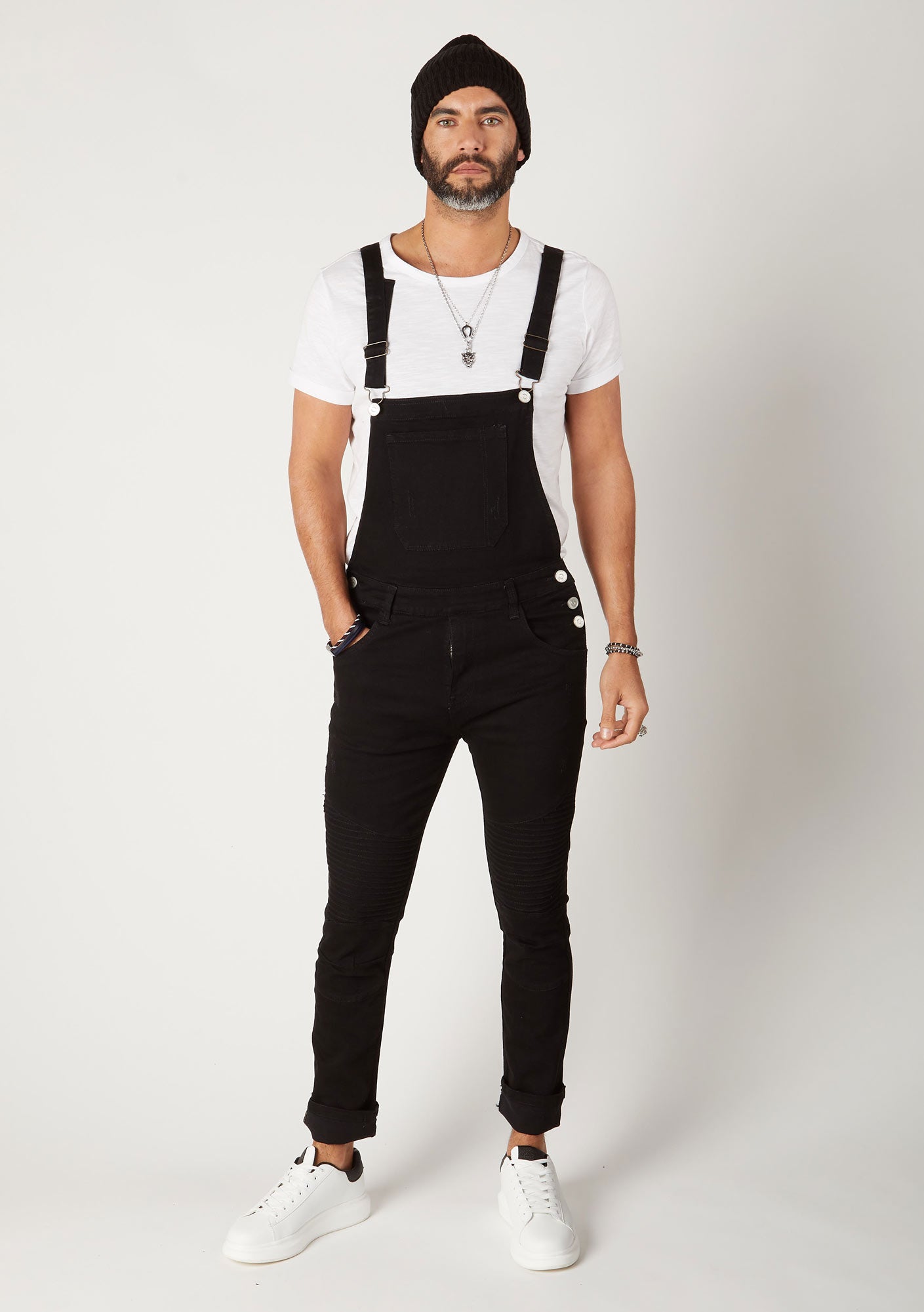 Front shot men's skinny fit black denim bib-overalls, model has hand in pocket