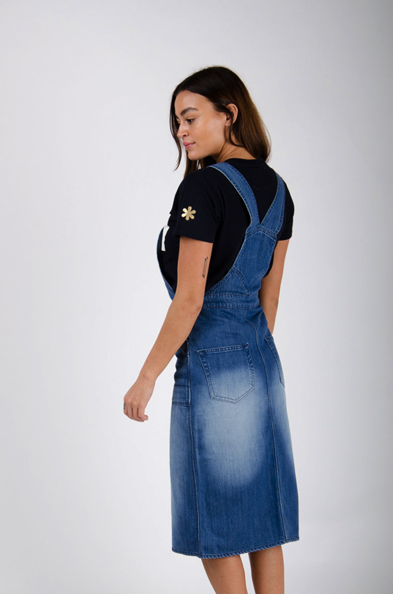 Back shot of dark blue washed organic cotton bib-overall midi dress with view of back pockets and straps.