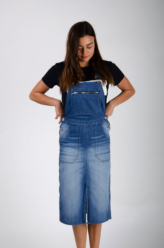 Top-half front view of washed denim organic cotton bib-overall midi dress with view of zip chest pocket