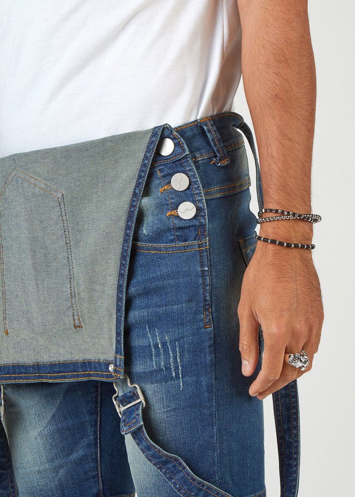 Close-up side view of 'Dave' bib-overalls with view of side pockets, strap buckle and side button fastenings.