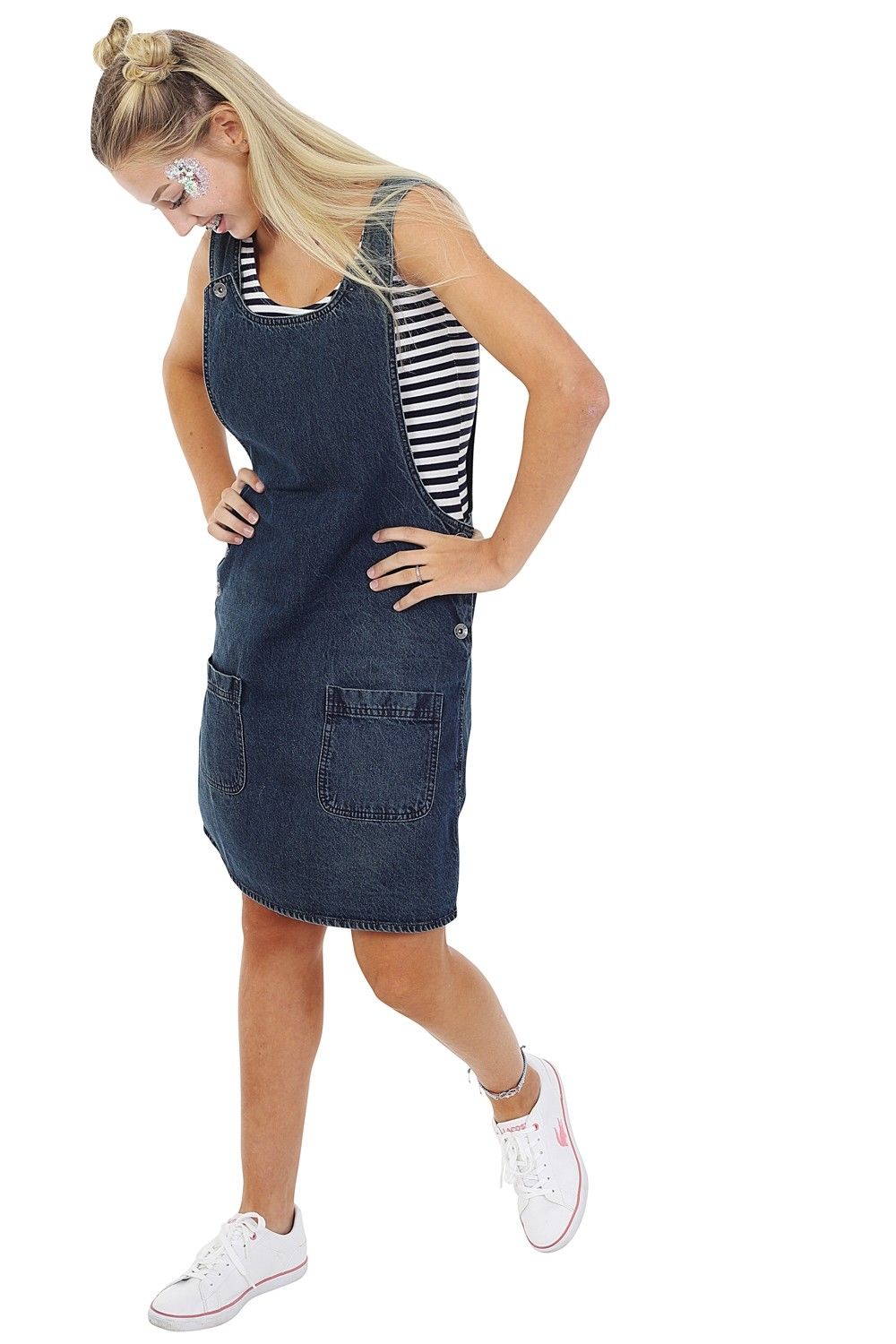 Angled front-side walking pose wearing ‘Renee’ style, short denim vintage wash pinafore dress with adjustable shoulder.