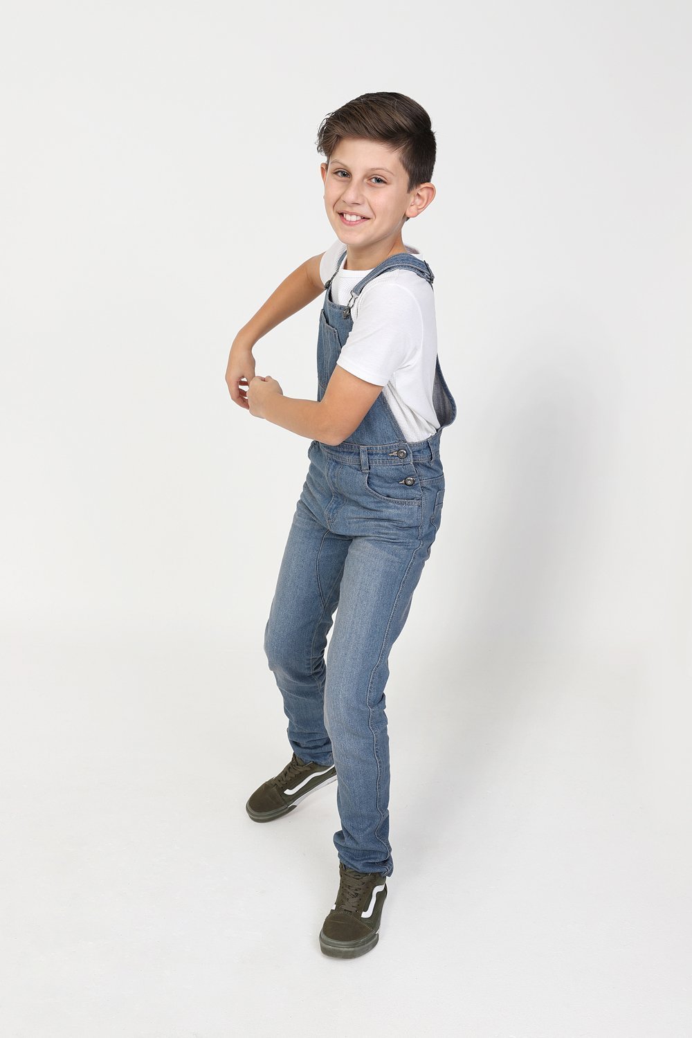 Full length side-view active pose of boy wearing durable slim-fit overalls.