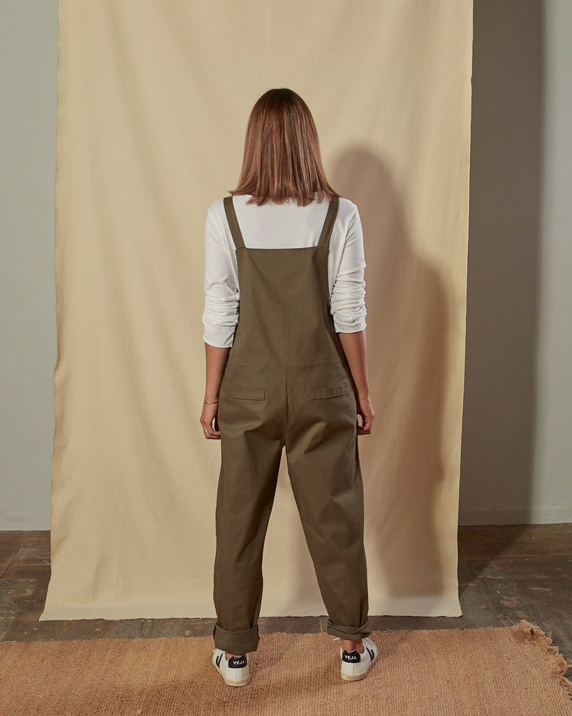 Full-length back view of Catherine khaki cotton twill dungarees with focus on mock pocket detailing.