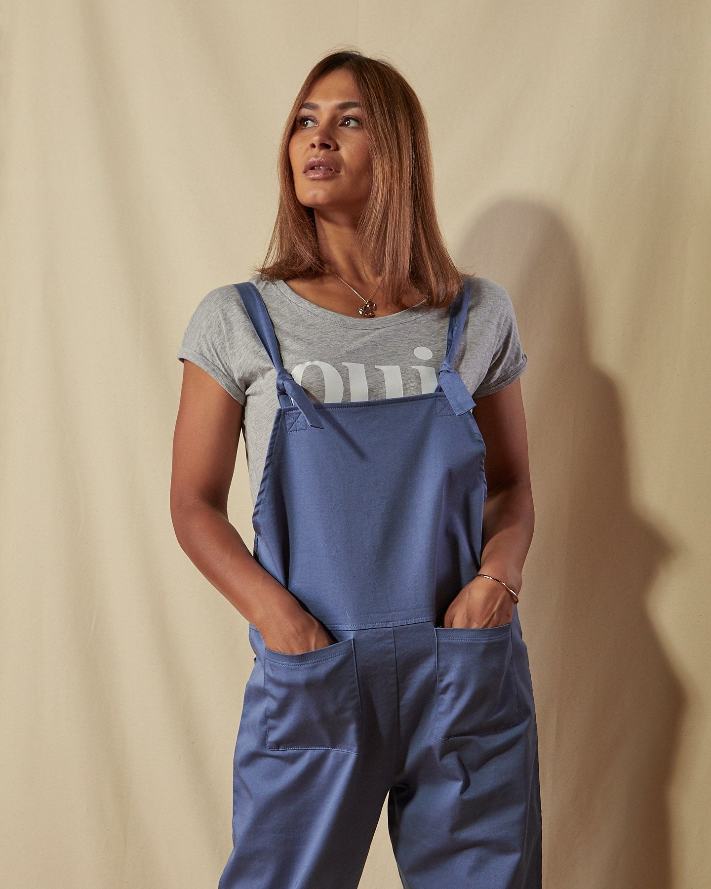 Close front view of pale blue dungarees with adjustable tie straps and front pockets