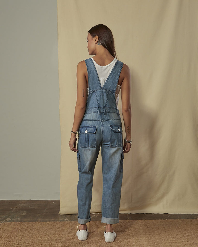 Back shot of women's stonewash denim cargo-pocket overalls with view of back button-down pockets.