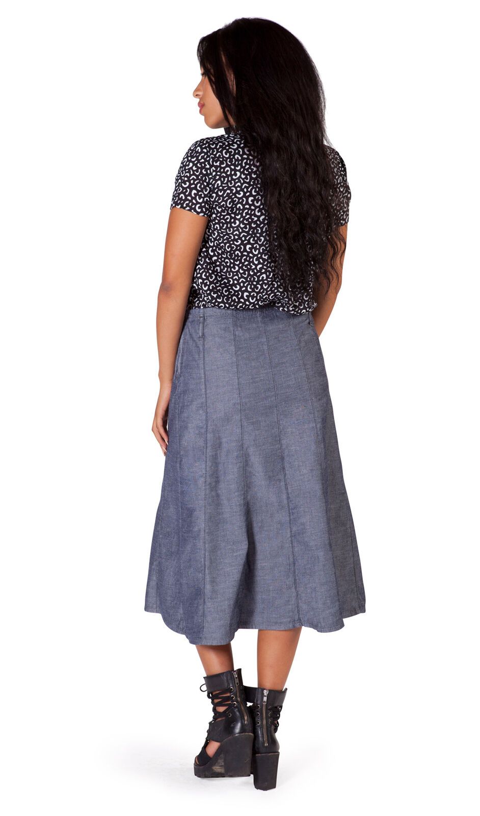 Full length back view of calf-length dark chambray denim skirt with clear view of flared silhouette.