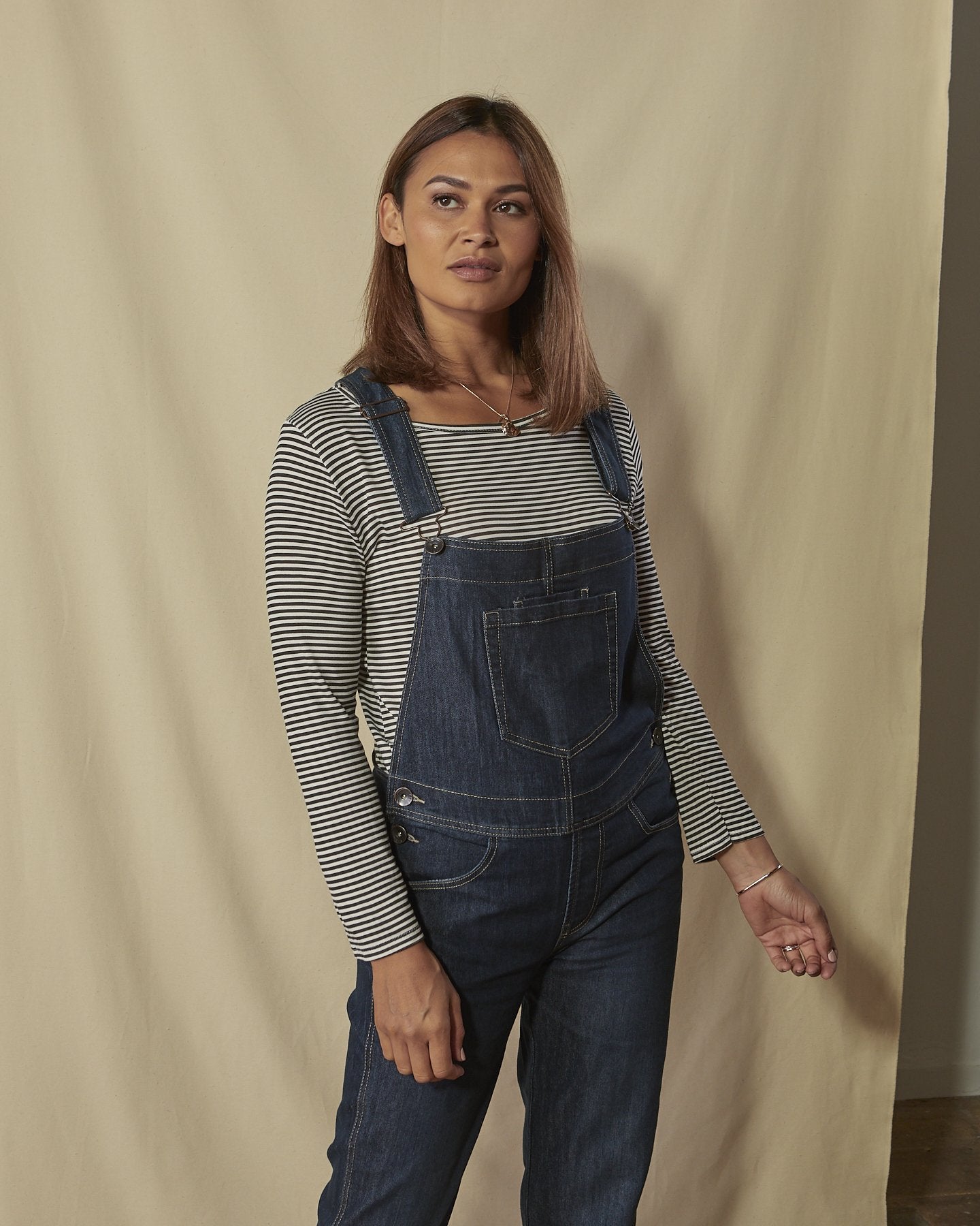 Two-thirds length front shot of Dottie dark-wash ladies regular fit dungarees with view of adjustable straps. 