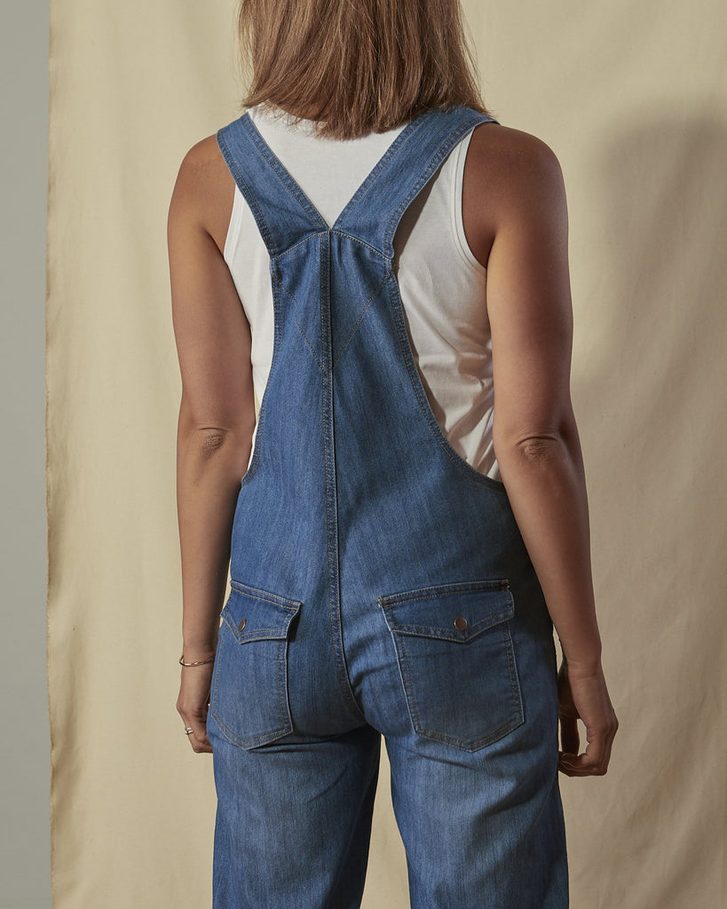 Close-up back shot of Dottie blue denim dungarees with clear view of back straps and back pockets.