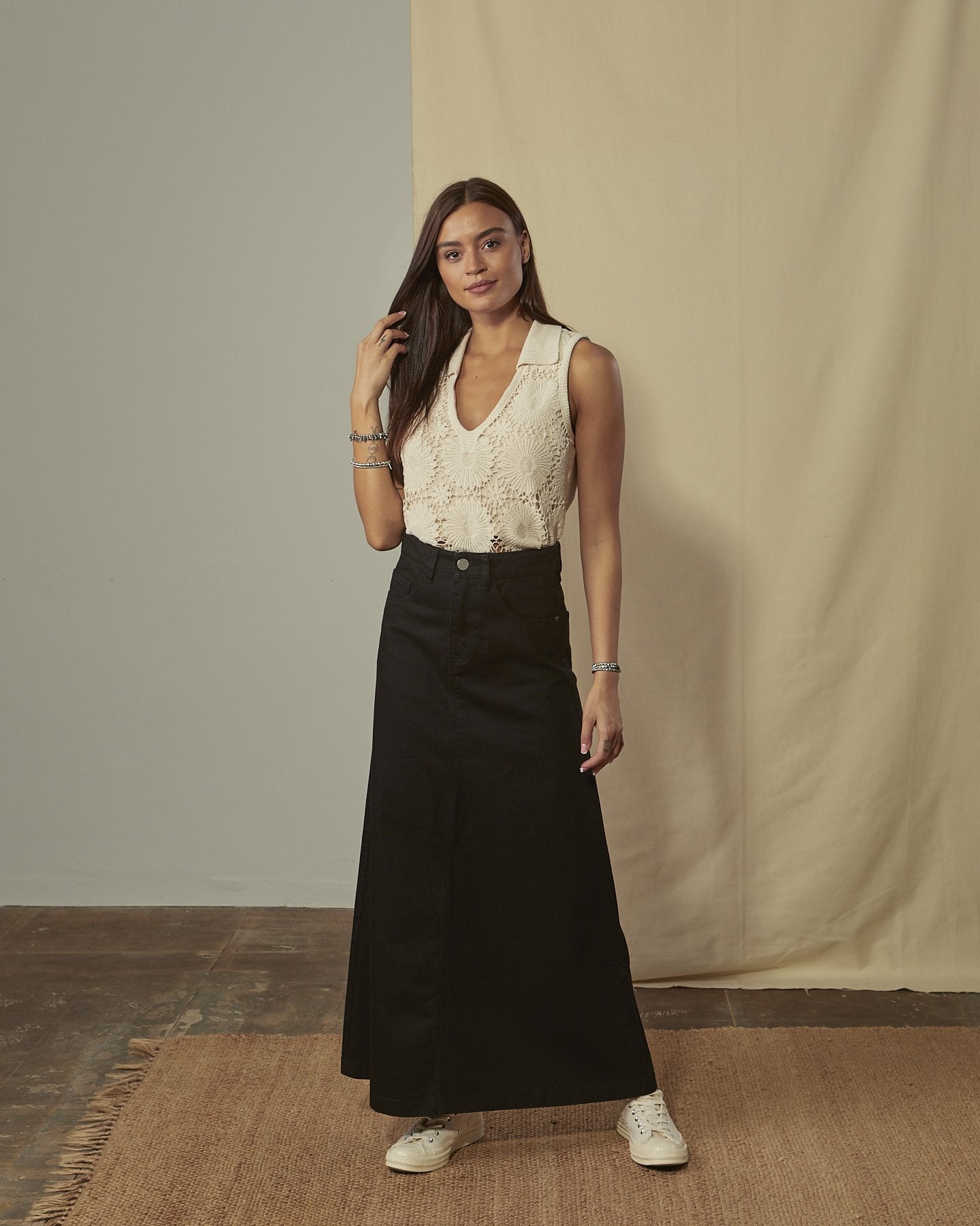 Full-length front view of Elspeth long black denim flared skirt showing front zip and button fastening.