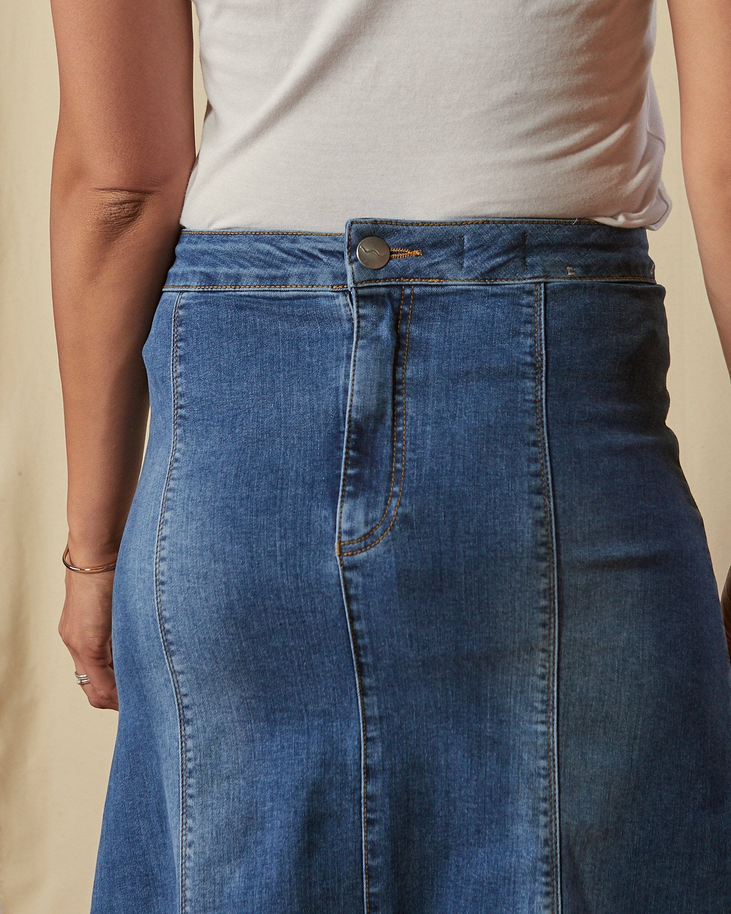Close-up of back of Evelyn stretch denim skirt with focus on back zip and button fastening. 