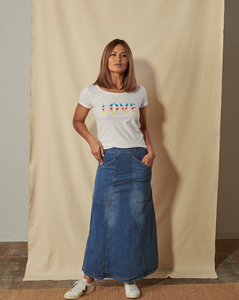 Full-length front view of model with hands in front pockets of blue Evelyn stretch denim skirt.