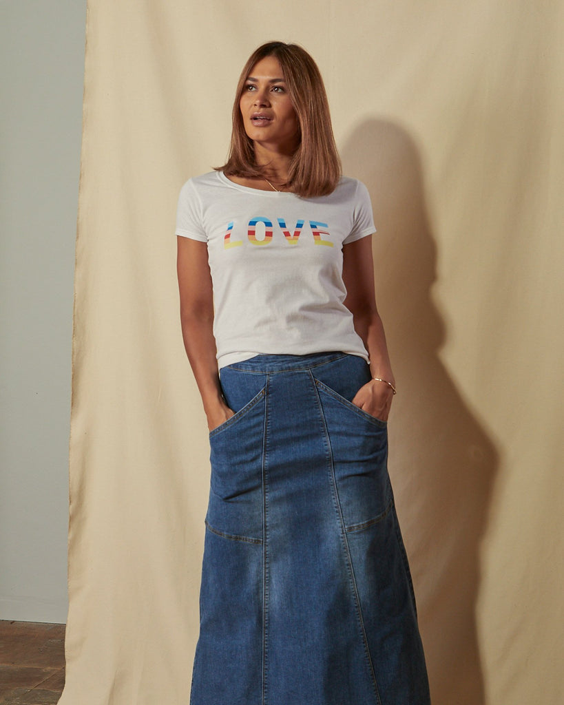 Three quarter length front view of model with hands in front pockets of blue Evelyn stretch denim skirt.