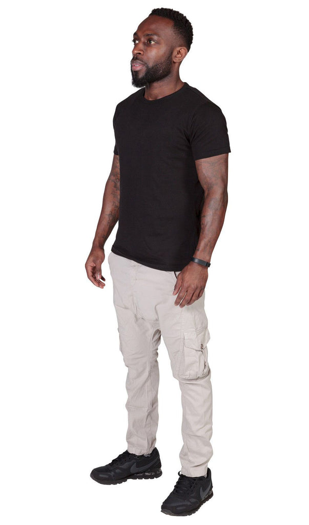 Angled front-side view of off-white ‘Finley’ style, casual cotton mix cargo trousers from Dungarees Online, with view of multiple pockets and tapered silhouette.