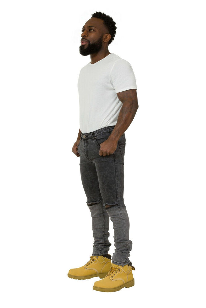 Side view wearing slim-fit, black denim jeans with ripped knees and thumbs in front pockets.