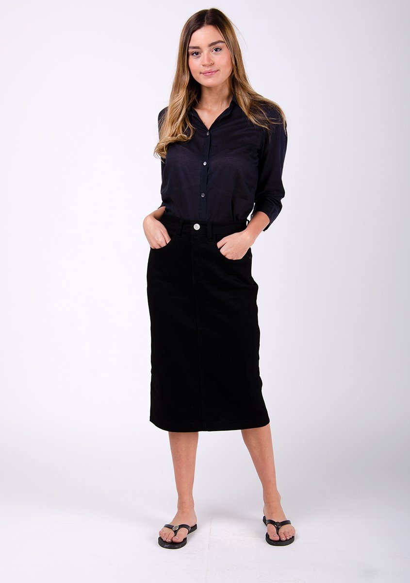 Full frontal pose with hands in front pockets, wearing medium length denim skirt.