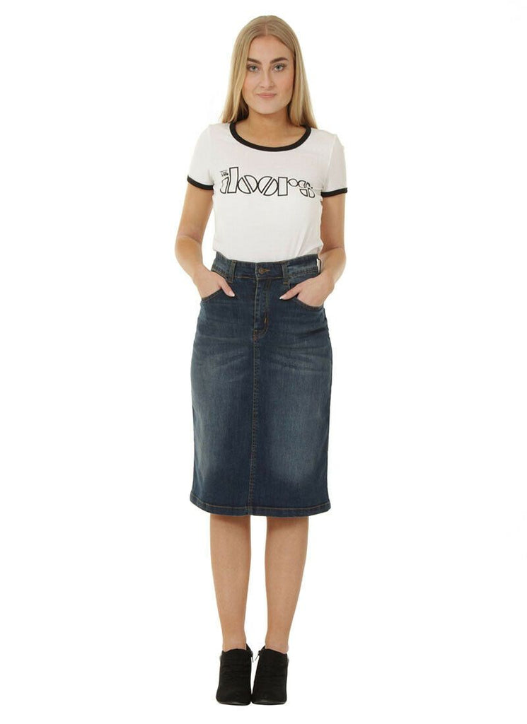 Full frontal view with hands in front pockets wearing classic below the knee, flexible denim skirt.