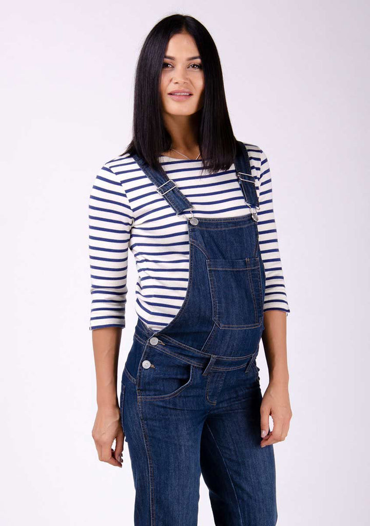Two-thirds pose focussing on front pockets, side buttons and adjustable straps of dark wash maternity dungarees