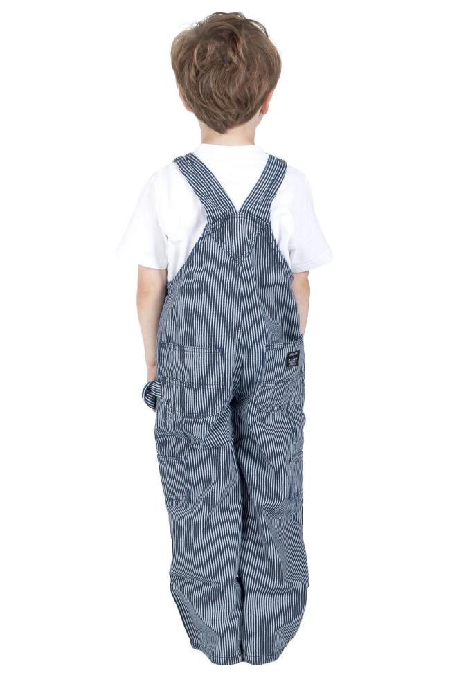 Full-length rear shot of toddler wearing pin-striped, cotton bib-overall with clear view of back pockets, logo label and back straps.
