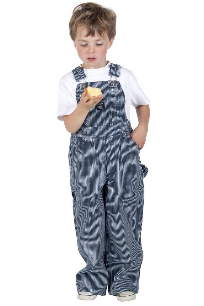 Full-length frontal of toddler wearing loose fitting, striped bib-overall with left hand in front pocket.
