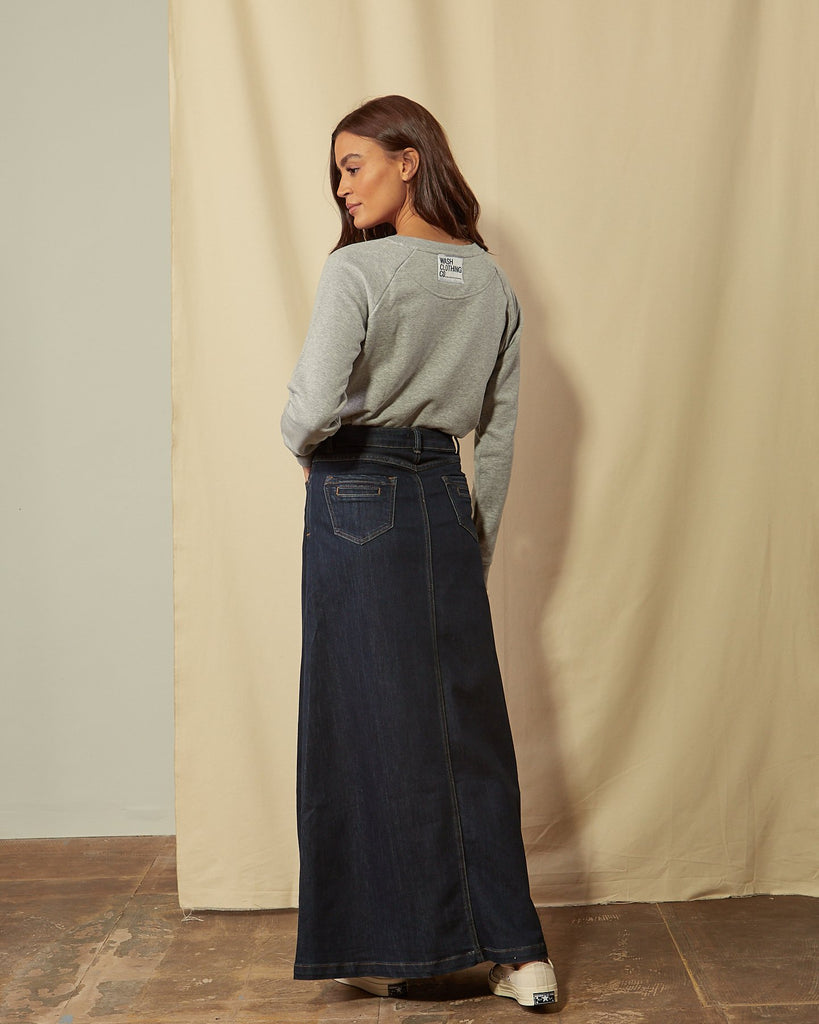 Full-length back view of dark blue flared style skirt accentuating stretch properties of denim with view of back pockets.
