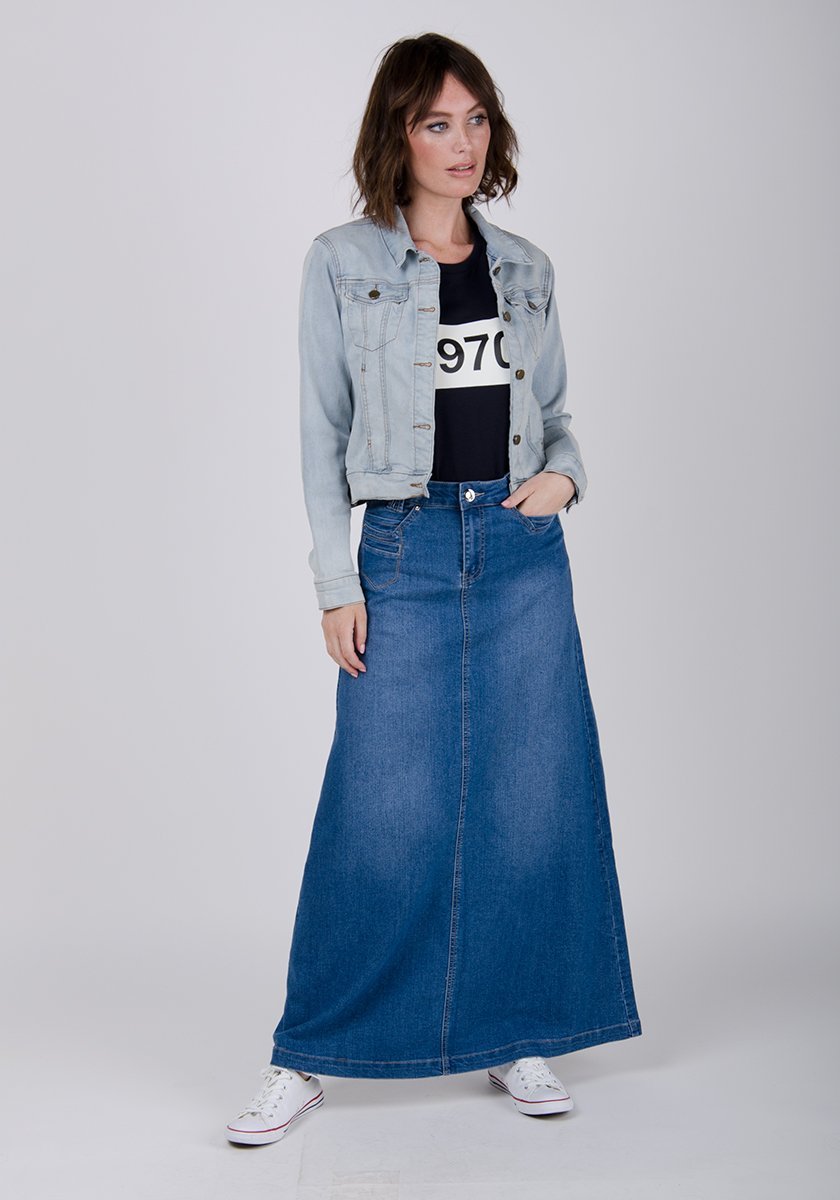 Full-length front view of model with hand in front pocket of stonewash denim skirt.