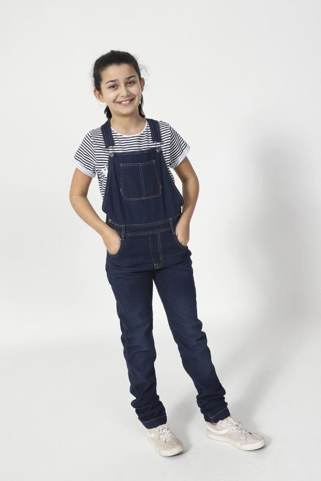 Full-frontal pose with hands in front pockets wearing Libby-style indigo dungarees with large bib pocket.