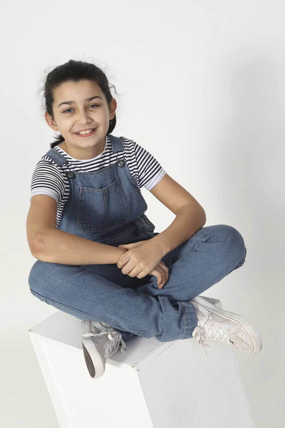 Girl sitting on box, wearing durable palewash, Libby style kids overalls.
